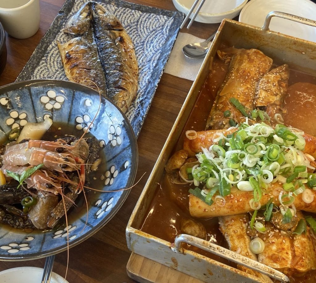 Traditional Jeju seafood dishes including grilled mackerel, braised fish, and fresh shrimp stew