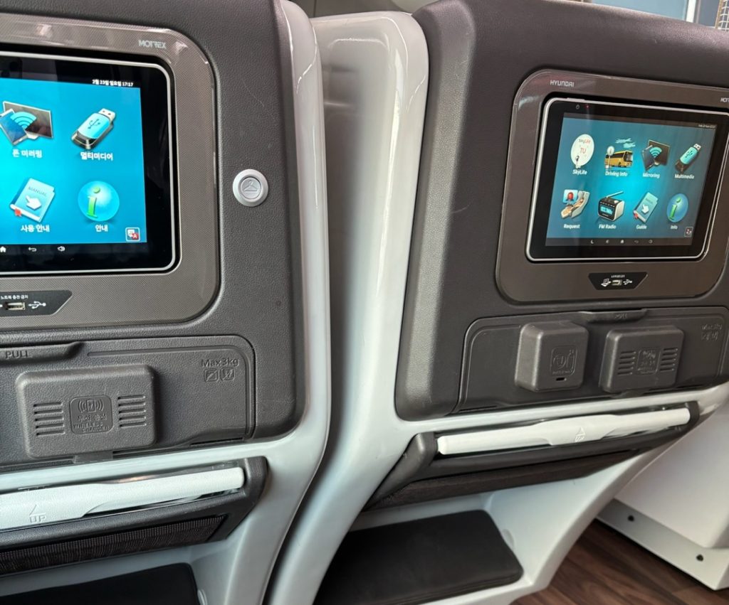 A fully reclining premium express bus seat with a privacy curtain and headrest, designed like a business-class pod.