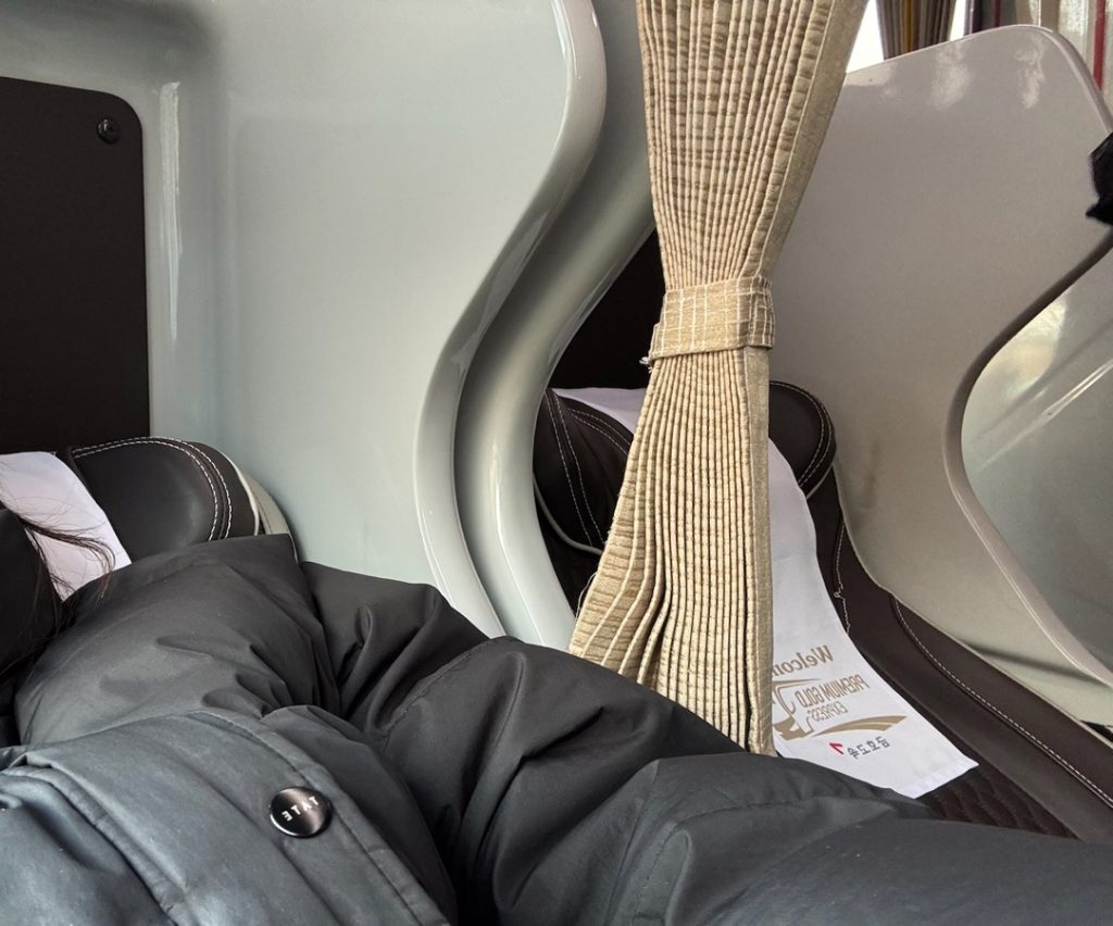 Premium express bus seats with built-in entertainment screens and footrests, showing a clean, modern interior.
