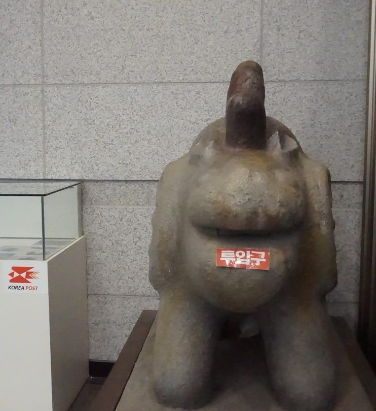 Slow postbox shaped like a stone animal statue inside National Gongju Museum, labeled “mail slot” in Korean.