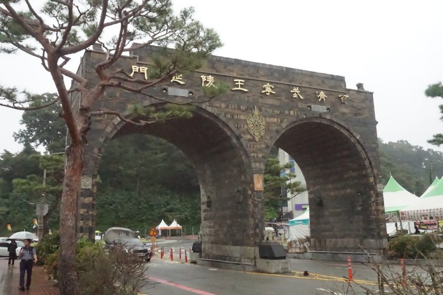 A large stone arch gateway near Gongsanseong Fortress in Gongju, with gold lettering and pine trees framing the scene on an overcast day.